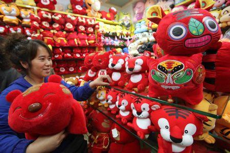A woman chooses tiger cloth puppet in a shop in Beijing December 29, 2009. Toys and decorations featuring tiger sell well as the Chinese lunar New Year of Tiger is nearing. [Xinhua]
