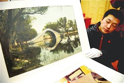 The staff shows the donation of the hand coloring old photo of Yudai Qiao (Jade Belt Bridge).[www.chinanews.com.cn]