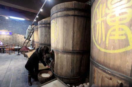 A visitor experiences extracting the grain from the imperial grain-storing cask on display inside the Imperial Granary Museum of Ming Dynasty of Nanxingcang Barn, which has been opened to public visitors, in downtown of Beijing, Jan. 16, 2010. Affluent exhibits reenacting the history of grains transport through the Grand Canal and the imperial barns storage are accessible to visitors, who can also experience the quern of stone mill some 600 years ago. (Xinhua/Luo Wei)