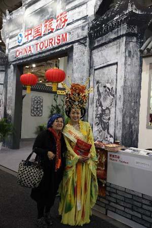 A visitor poses for a photo with a Chinese worker in traditional costume at the Chinese pavilion during the International Tourism Bourse in Berlin, capital of Germany, March 12, 2010.(Xinhua/Luo Huanhuan)