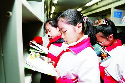 南通市城中小学三里墩校区学生在校园体验“阅读巴士”流动图书车阅读服务。许丛军摄/光明图片