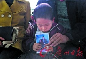 两人的儿子由外公外婆照顾,他手捧一岁时和父亲的合照。