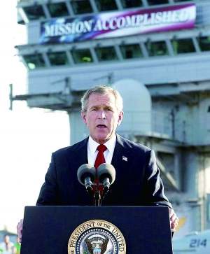 布什身后横幅上写着“任务完成”，在今天看来，这不啻一个莫大的讽刺。