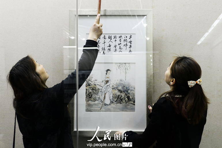 两名工作人员正从展廊里取下一幅被藏家收购的国画作品。