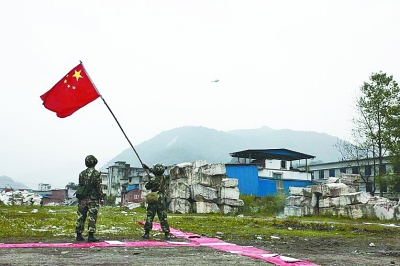 两名战士在宝兴县灵关镇挥舞国旗引导救援直升机。 新华社图