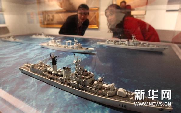  12月25日，工作人员（左）在上海中国航海博物馆的预展上向参观者介绍部分护航舰艇模型。新华网图片 裴鑫 摄