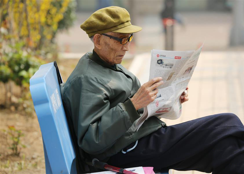 周智夫在干休所小花园中阅读报纸（2015年4月9日摄）。