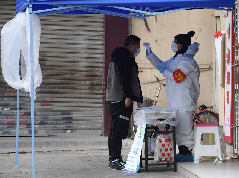　　武汉市园林局支援德望社区的一位下沉工作人员在值守的小区门口为来访者测量体温（2月10日摄）。新华社记者 李贺 摄