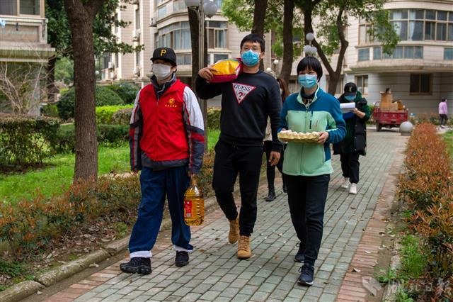 武汉市洪山区省电社区，武汉市税务局下沉90后党员胡俊昊(左二)同社区工作者为居民送去生活物资。