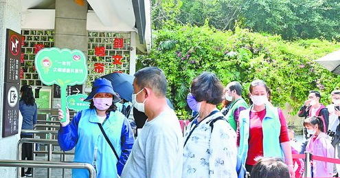 在植物园入口处，工作人员向游客宣导文明健康风景线“一米线”。
