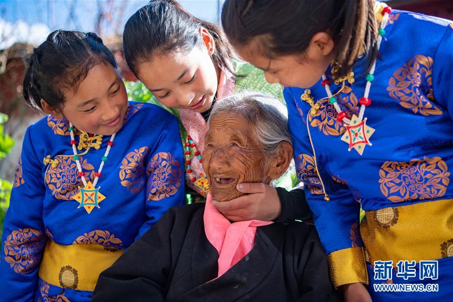 109岁的索朗卓玛和曾孙女旦增宗吉(右一)、旦增央吉(左一)、丹增曲吉在自家的院子里（3月24日摄）。