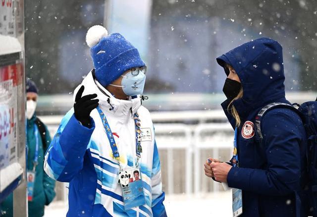 北京2022年冬奧會和冬殘奧會，青年志愿者在媒體中心擺渡車站點為外國工作人員提供咨詢服務。