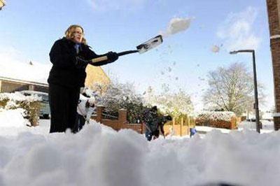 Laura Bickerdike clears snow from a road in Kirby Hill, northern England January 6, 2010. REUTERS/Nigel Roddis