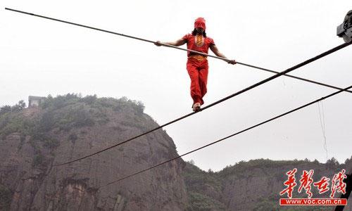 Askar, a student of legendary Chinese tightrope walker, Adili Wuxor, has begun his challenging journey, a 700-meter high blindfold backward walk, in Central China’s Shiniuzhai geo-park in Hunan province.