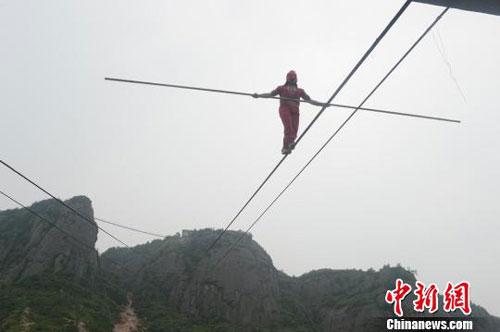 Askar, a student of legendary Chinese tightrope walker, Adili Wuxor, has begun his challenging journey, a 700-meter high blindfold backward walk, in Central China’s Shiniuzhai geo-park in Hunan province.