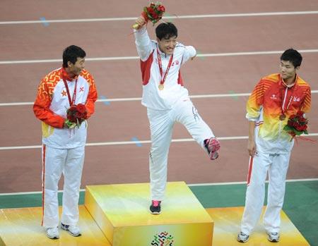 Olympic gold medalist Liu Xiang (C) from Shanghai jubilates while Ji Wei(L) of the People's Liberation Army (PLA) team and Shi Dongpeng from Hebei watch on the podium after the men's 110m hurdles of athletics at the 11th Chinese National Games in Jinan, east China's Shandong Province, Oct. 25, 2009. [Xinhua] 