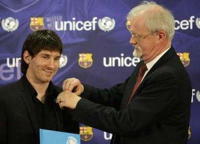 Barcelona's player Lionel Messi of Argentina receives a badge from UNICEF Private Fundraising and Partnerships Director Philip O'Brien at the Nou Camp stadium in Barcelona March 11, 2010. He is the first Barcelona player to be awarded as a UNICEF Goodwill Ambassador and will work to promote children's rights.REUTERS/Gustau Nacarino (SPAIN - Tags: SPORT SOCCER SOCIETY)