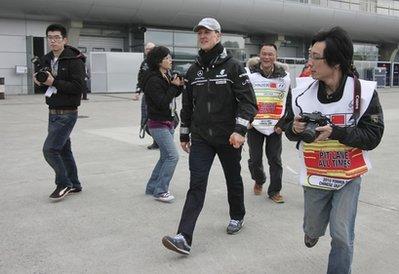 Mercedes Formula One driver Michael Schumacher, center, of Germany walks through the F1 Paddock at the Shanghai International Circuit on his arrival at the Chinese Formula One Grand Prix in Shanghai, China, Thursday, April 15, 2010.(AP Photo/Eugene Hoshiko)