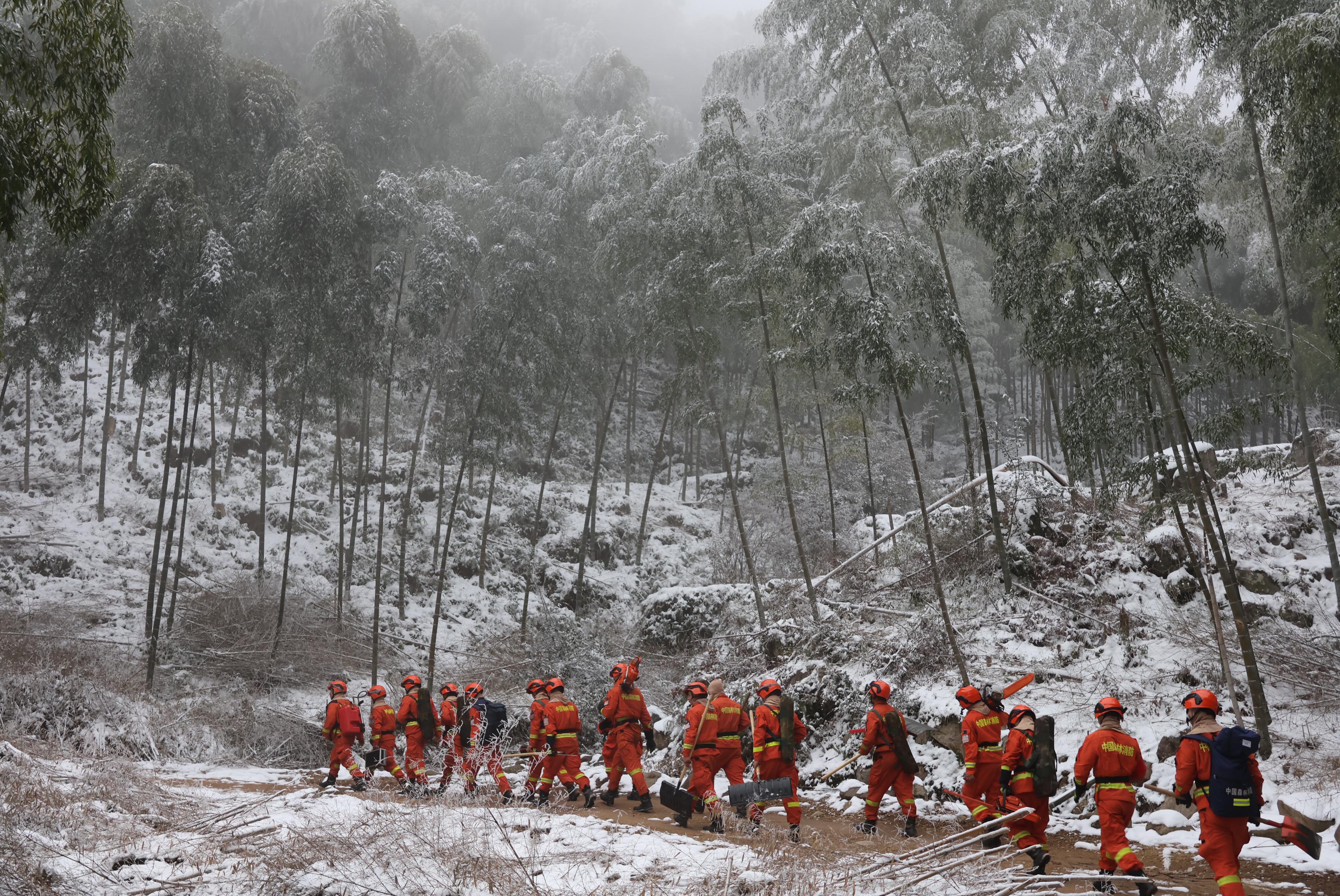 消防员携带除冰工具徒步接近救援现场 何思炎摄
