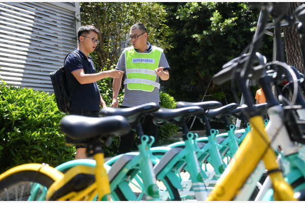 在福州街头，第三方合作企业工作人员（右）与共享单车企业代表在交流共享单车的停放管理办法。新华社图