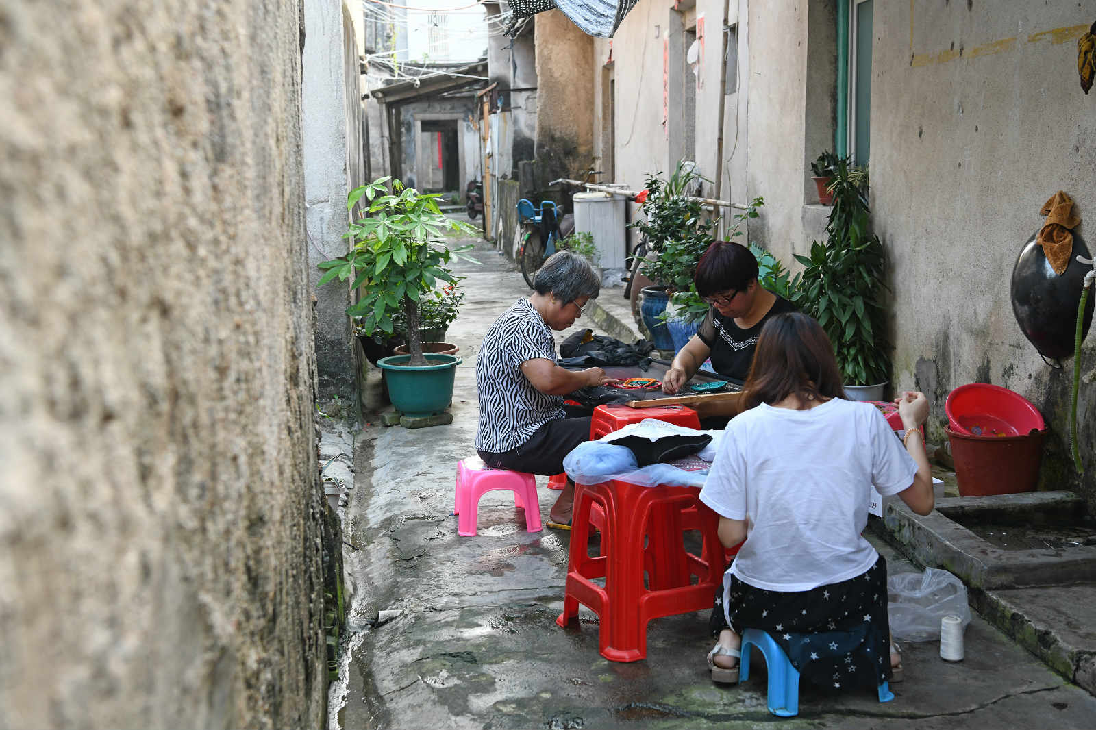 Wei Jingming (C) sews a piece of needlework with her daughter-in-law and cousin in Tahou Village of Linxi Township, Chaozhou, south China