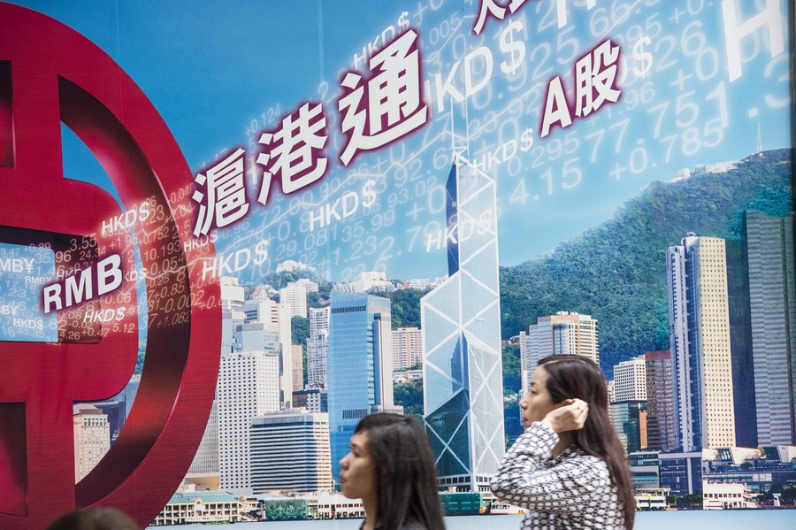 Citizens walk past a billboard advertising the Shanghai-Hong Kong Stock Connect, in south China’s Hong Kong, April 8, 2015. (Xinhua/Lui Siu Wai)