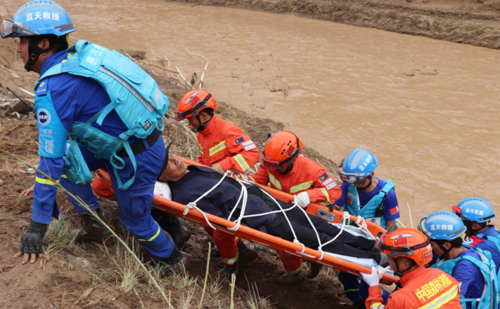 7月16日，甘肃省庆阳市庆城县翟家河乡消防救援人员同蓝天救援队员人员一起转移受伤群众。（甘肃省森林消防总队平凉支队供图）