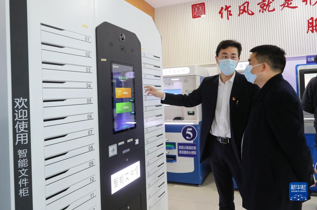 上海市闵行区七宝镇社区事务受理服务中心的工作人员（左）向前来办事的居民介绍智能文件柜的使用方法（2021年3月3日摄）。