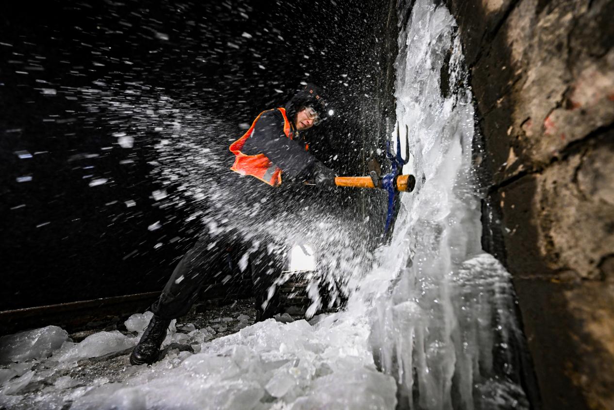 　　工友正在敲击冻结在隧道内的侧壁冰柱。（图片由太原局太原工务段赵哲昌提供）