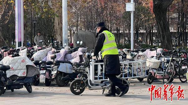  近日，武漢一所大學校園內，校園保安在整理隨意停放的電動車。