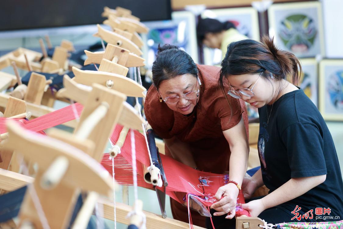 非遗传承人汪绍碧向重庆旅游职业学院学生传授西兰卡普织锦技艺。近年来,该校把10多项非物质文化遗产引进校园,并聘请非遗传承人担任客座教授,为学生传授非遗制作技艺,培养非遗传承人。(杨敏摄/光明图片)