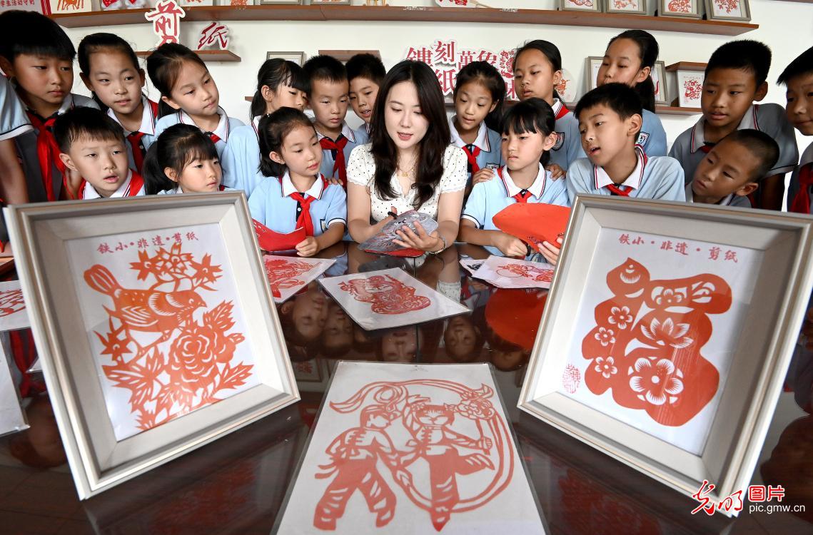 河北省邯郸市复兴区铁路小学开展“非遗进校园、文化有传承”主题活动,同学们亲身体验葫芦烙画、剪纸等非遗技艺,近距离感受中华传统文化的魅力。图为老师向学生们讲解剪纸技巧。(郝群英摄/光明图片)